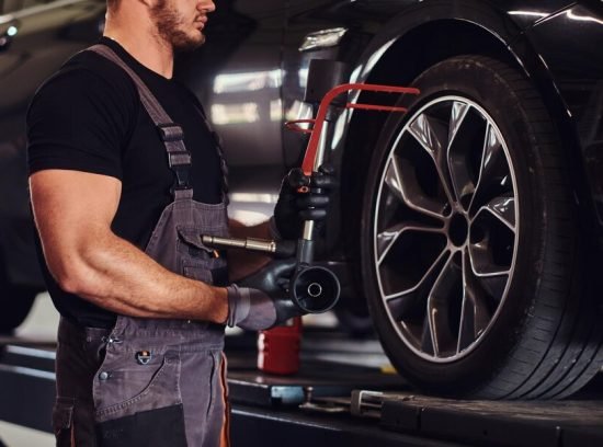 muscular-man-is-fixing-car-s-wheel-with-special-tool-auto-service_613910-17086