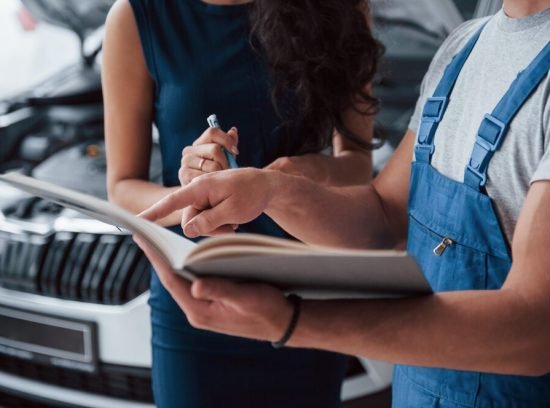 your-signature-please-woman-auto-salon-with-employee-blue-uniform-taking-her-repaired-car-back_146671-16116